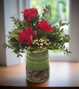 Broadway flowers include roses and greens in simple cylinder vase.